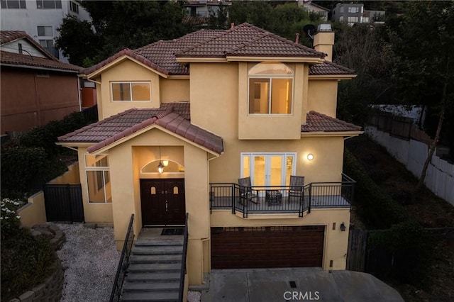 mediterranean / spanish-style house featuring a tiled roof, fence, and stucco siding