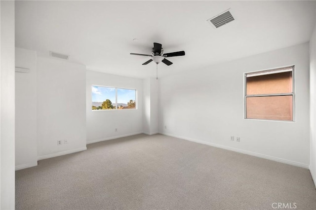 empty room with light carpet, ceiling fan, visible vents, and baseboards