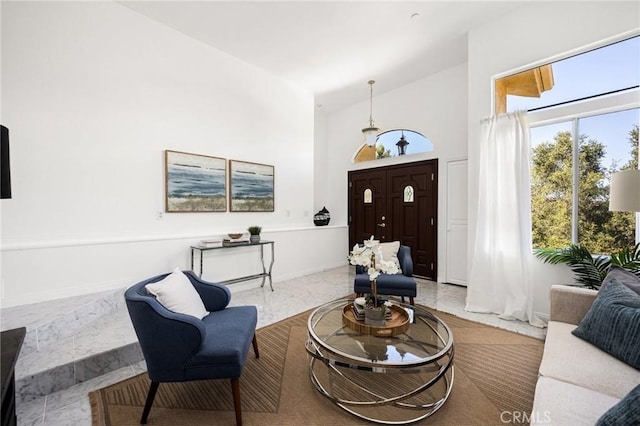 sitting room with high vaulted ceiling and baseboards