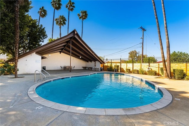 pool with a patio area and fence