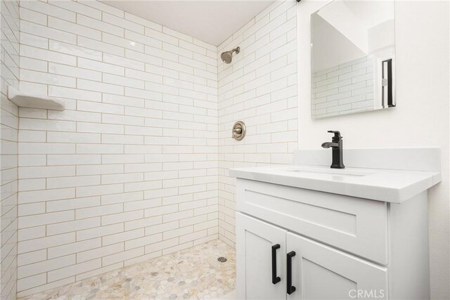 full bath with a tile shower and vanity