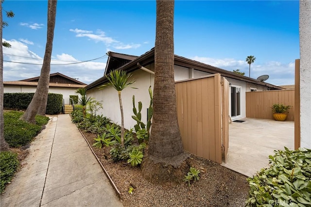 view of home's exterior featuring stucco siding, fence, and a patio