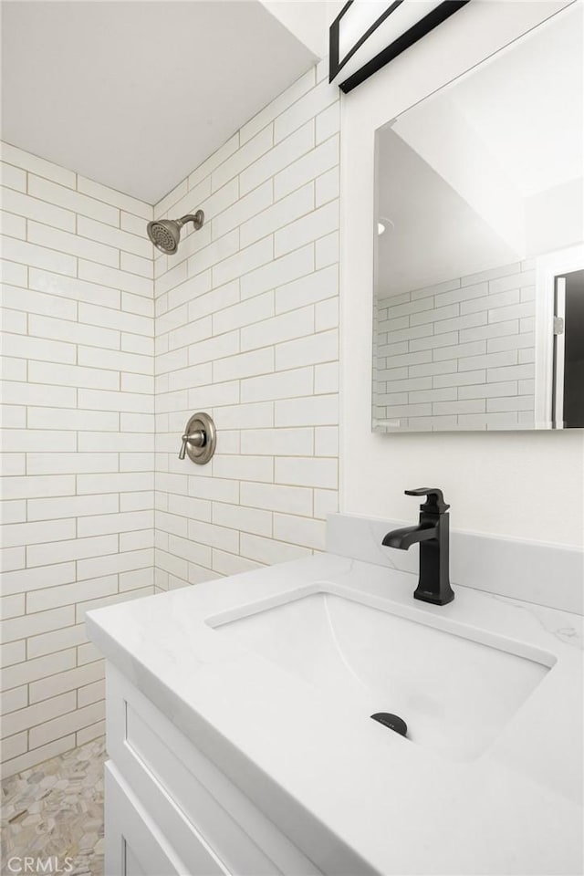 bathroom featuring a tile shower, a sink, and tile walls