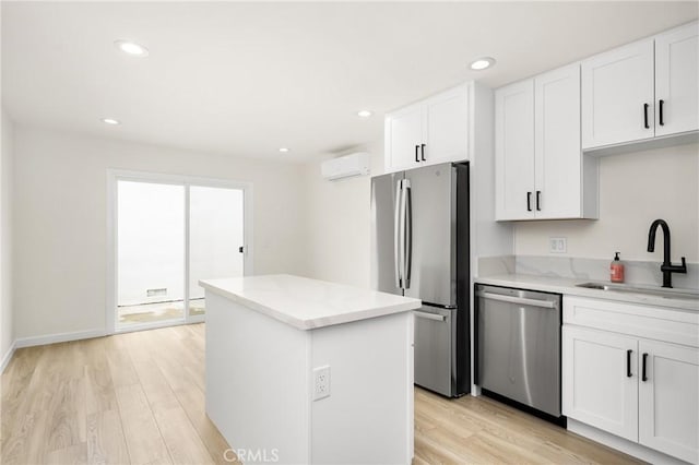 kitchen with a center island, light wood finished floors, stainless steel appliances, an AC wall unit, and a sink