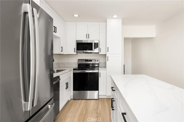 kitchen featuring light wood finished floors, white cabinetry, light stone counters, and stainless steel appliances