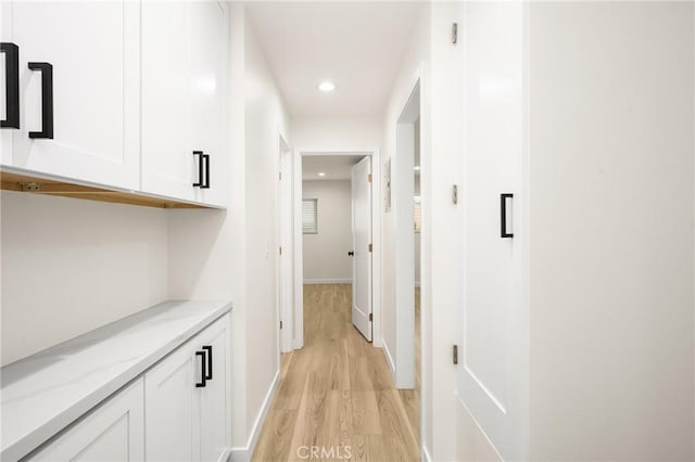 hallway with recessed lighting, light wood-style flooring, and baseboards