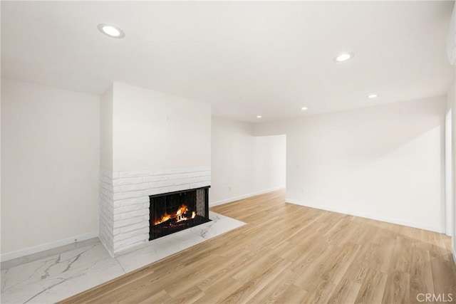 unfurnished living room featuring recessed lighting, a fireplace, light wood-style flooring, and baseboards