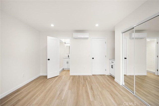 unfurnished bedroom featuring an AC wall unit, light wood finished floors, recessed lighting, and baseboards