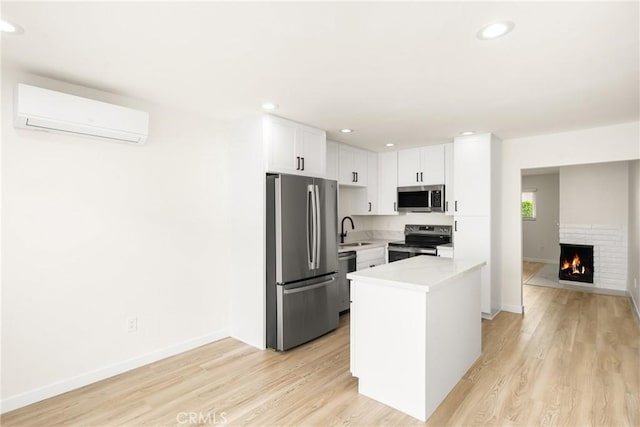 kitchen with a wall unit AC, light wood-style flooring, appliances with stainless steel finishes, light countertops, and a sink