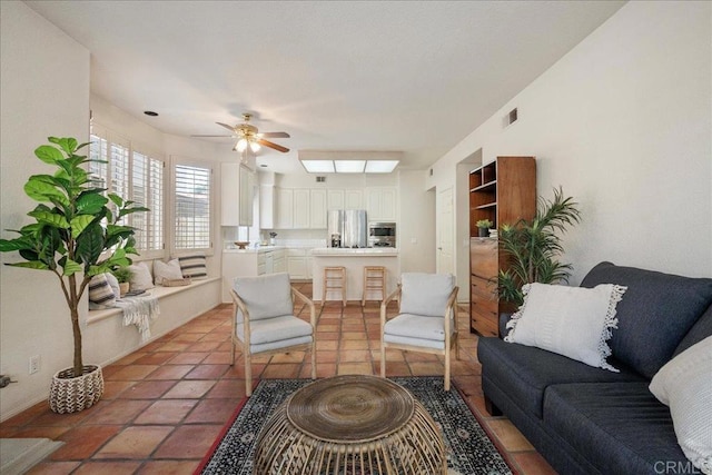 living area featuring a skylight, visible vents, ceiling fan, and light tile patterned floors