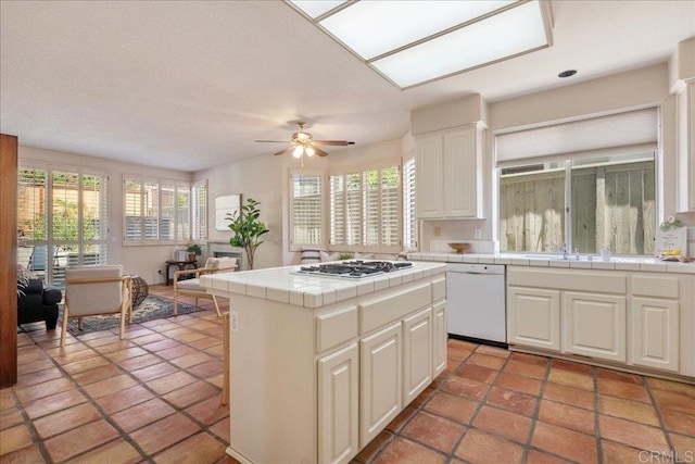 kitchen with tile countertops, white appliances, white cabinetry, and a healthy amount of sunlight