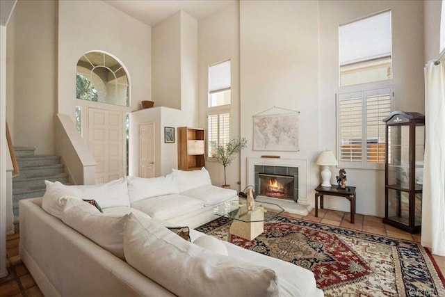 tiled living room featuring stairs, a high ceiling, and a fireplace