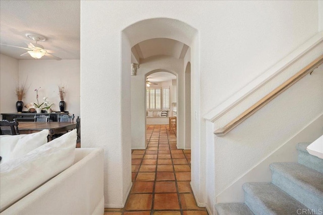 hall with arched walkways, light tile patterned flooring, and stairs