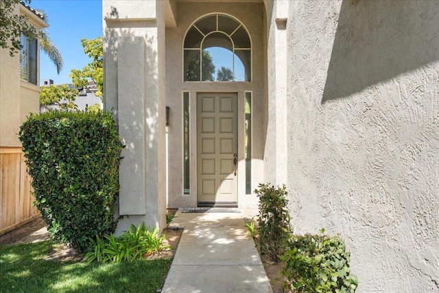 entrance to property featuring fence and stucco siding