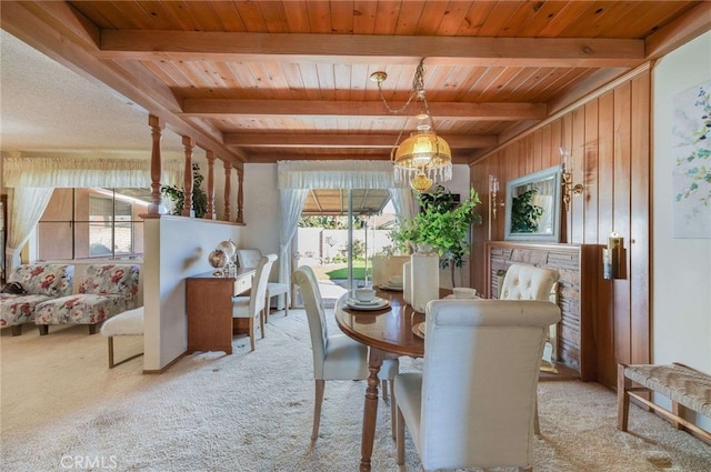 dining space with beam ceiling, a notable chandelier, light colored carpet, and wooden ceiling