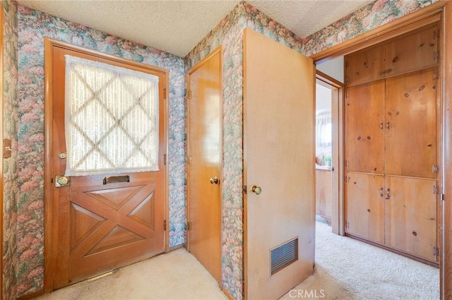 interior space featuring visible vents, carpet floors, a textured ceiling, and wallpapered walls