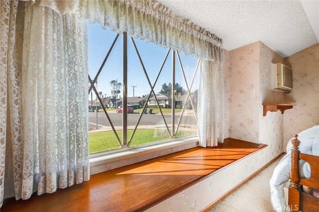 details with an AC wall unit, a textured ceiling, a residential view, wallpapered walls, and baseboards