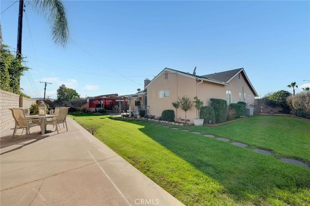 view of side of home with a yard, a patio area, a fenced backyard, and stucco siding