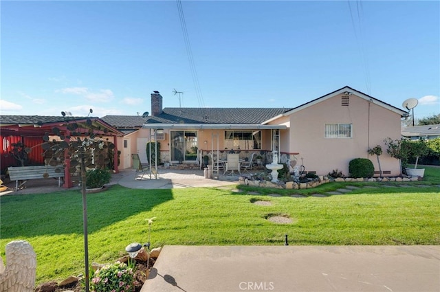 back of house with stucco siding, a lawn, a chimney, stone siding, and a patio