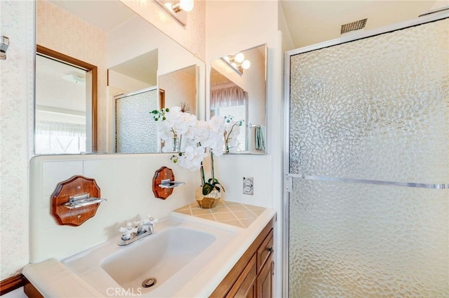 bathroom with a wealth of natural light, a shower stall, vanity, and backsplash