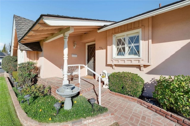 entrance to property with stucco siding and a shingled roof