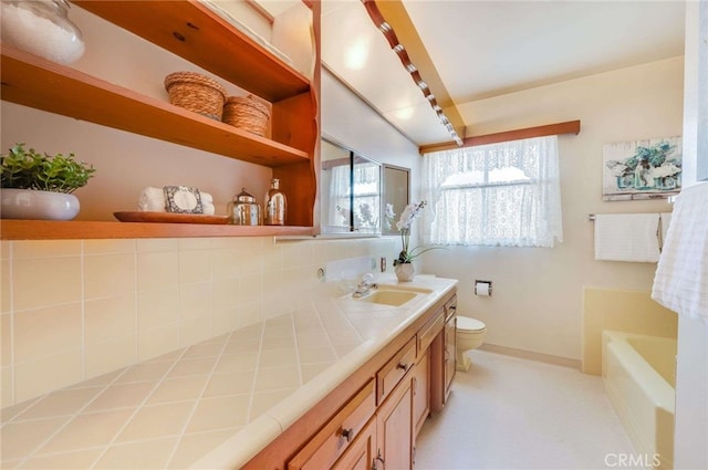 full bath with baseboards, toilet, vanity, and a bathing tub