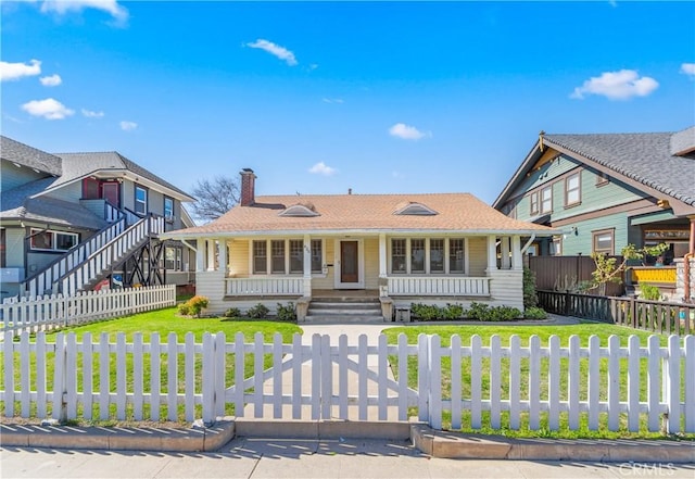 view of front of home with a porch, a front yard, a chimney, and a fenced front yard