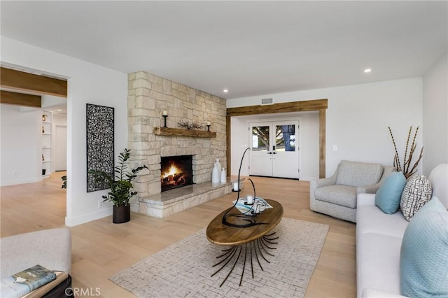 living room with recessed lighting, a fireplace, visible vents, light wood-style floors, and french doors