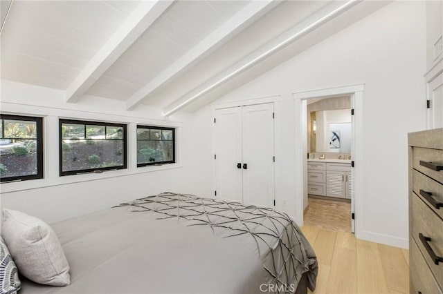 bedroom featuring a closet, connected bathroom, lofted ceiling with beams, and light wood finished floors