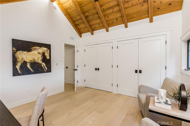 interior space with visible vents, light wood-style flooring, wood ceiling, beamed ceiling, and baseboards