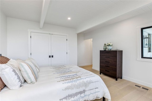 bedroom featuring beam ceiling, a closet, visible vents, light wood-type flooring, and baseboards