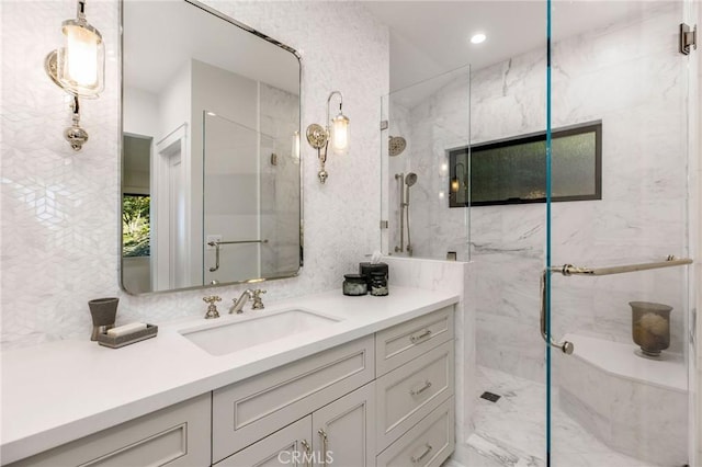 full bath with a marble finish shower and vanity