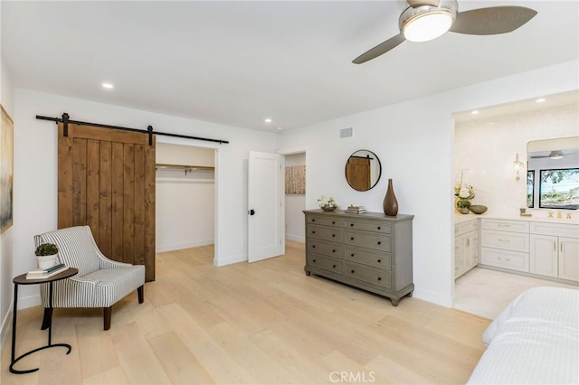 bedroom featuring a barn door, ensuite bath, light wood-style flooring, and recessed lighting