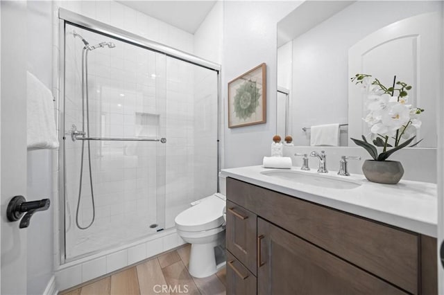 full bathroom with toilet, a stall shower, wood finished floors, and vanity