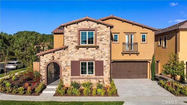 mediterranean / spanish-style house featuring stone siding, decorative driveway, an attached garage, and stucco siding