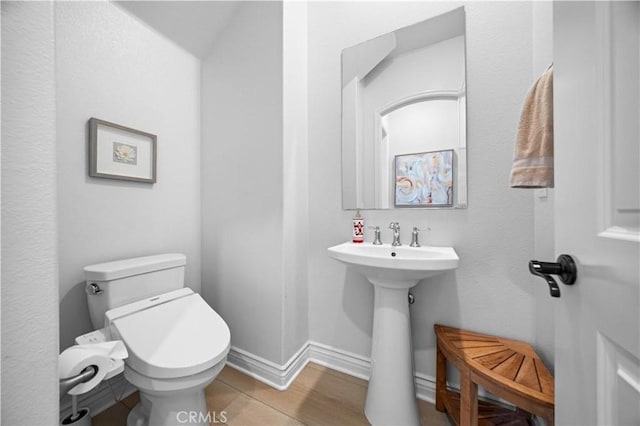 bathroom featuring baseboards, a sink, and toilet