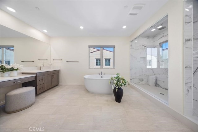 bathroom featuring a marble finish shower, recessed lighting, a soaking tub, vanity, and baseboards