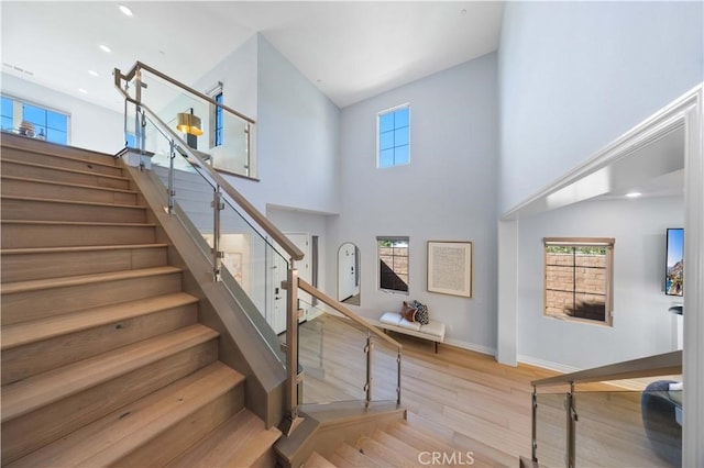 stairs with a high ceiling, baseboards, and wood finished floors