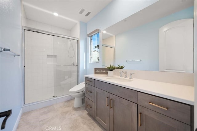 bathroom featuring toilet, vanity, a shower stall, and visible vents