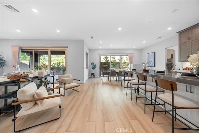 interior space featuring recessed lighting, visible vents, light wood-style floors, a kitchen breakfast bar, and baseboards