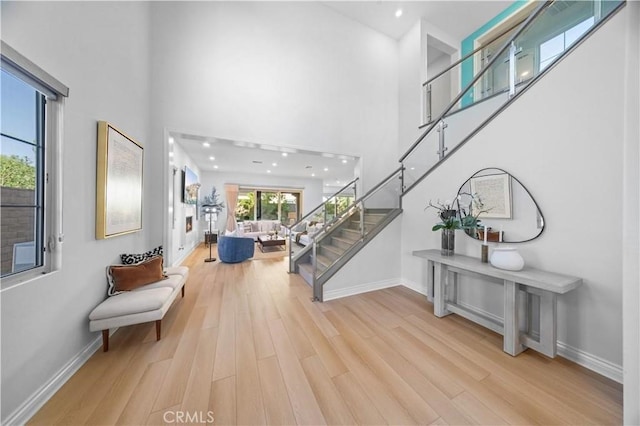 entrance foyer featuring stairs, a high ceiling, wood finished floors, and baseboards