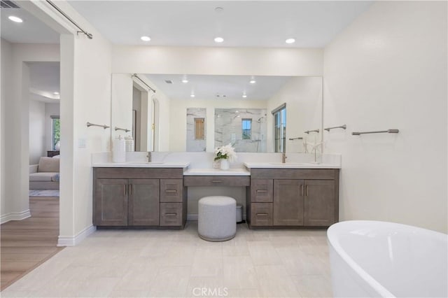 bathroom with recessed lighting, a sink, two vanities, a soaking tub, and a stall shower