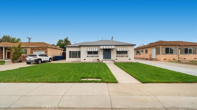 view of front of house with concrete driveway, a front lawn, and stucco siding