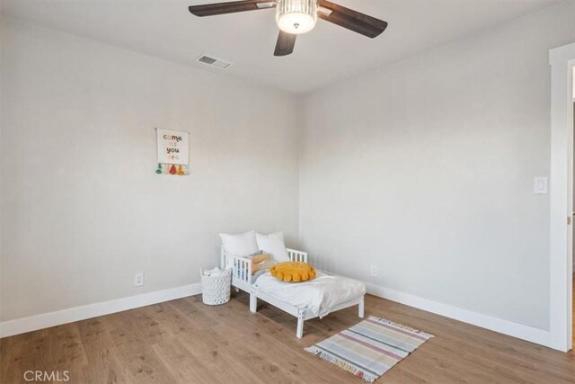 bedroom with visible vents, baseboards, wood finished floors, and a ceiling fan