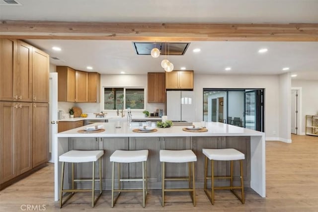 kitchen with recessed lighting, a kitchen bar, light wood finished floors, and freestanding refrigerator