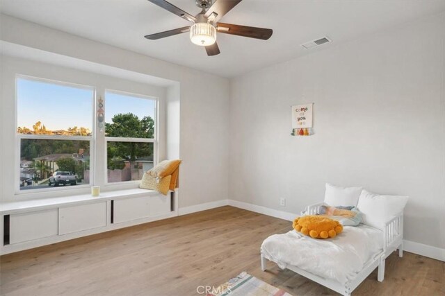 living area with visible vents, baseboards, light wood-style floors, and a ceiling fan