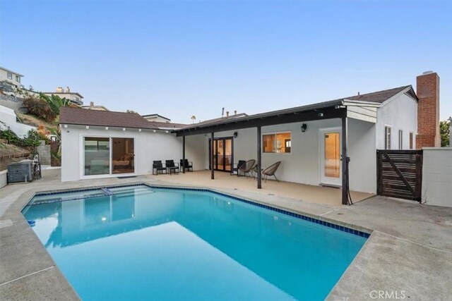 back of house featuring stucco siding, fence, a patio, and a fenced in pool