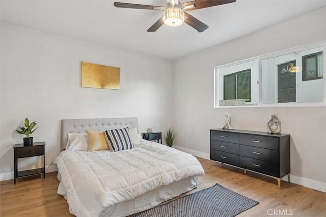 bedroom with a ceiling fan, baseboards, and light wood-type flooring