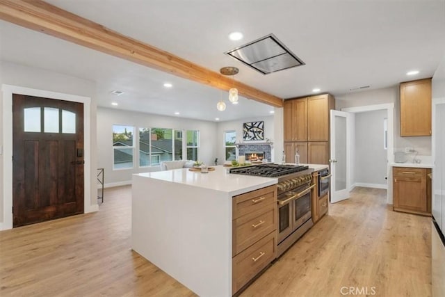 kitchen featuring range with two ovens, light wood-style flooring, beamed ceiling, and a lit fireplace