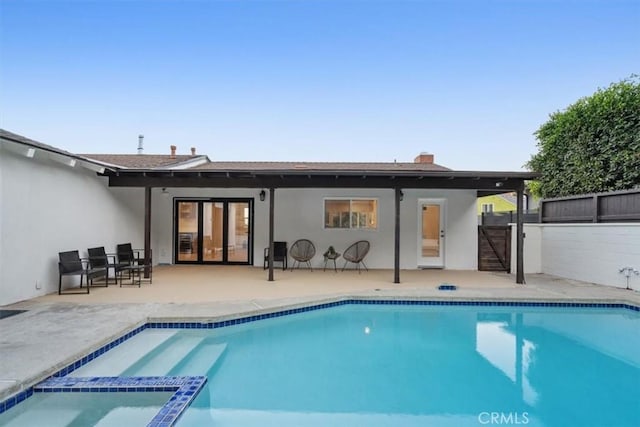 rear view of house featuring a patio area, stucco siding, a pool with connected hot tub, and fence